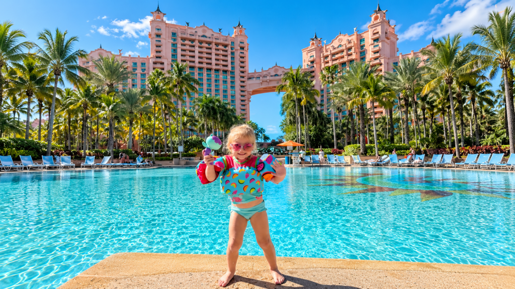 Child beside the turquoise Royal Baths pool at Atlantis Paradise Island, Bahamas, with the Royal Towers behind her.