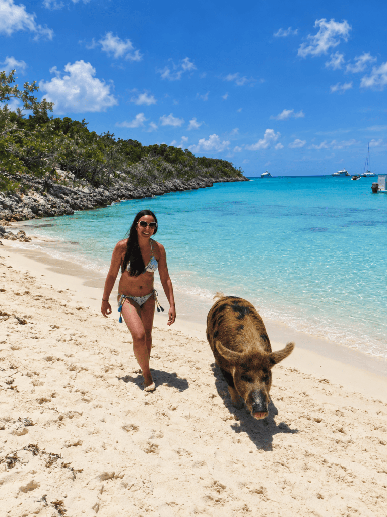 Katrina DeGrande of Bahama Mama Travel Co. walking beside a pig on Big Major Cay in Exuma, Bahamas.